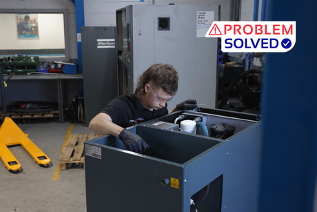 PPS engineer performing maintenance on an industrial air compressor inside a workshop, wearing safety glasses and gloves. A 'Problem Solved' graphic is displayed in the top-right corner.